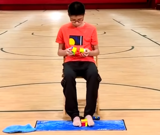 Подросток установил мировой рекорд, собрав 3 кубика Рубика одновременно, причём один из них ногами